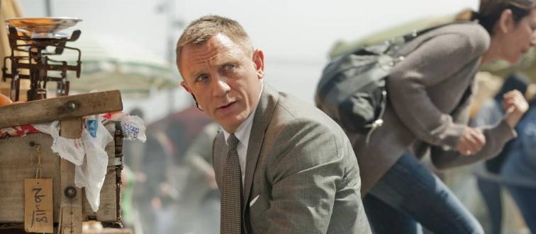 Daniel Craig kneeling on street with empty pistol as James Bond in Skyfall