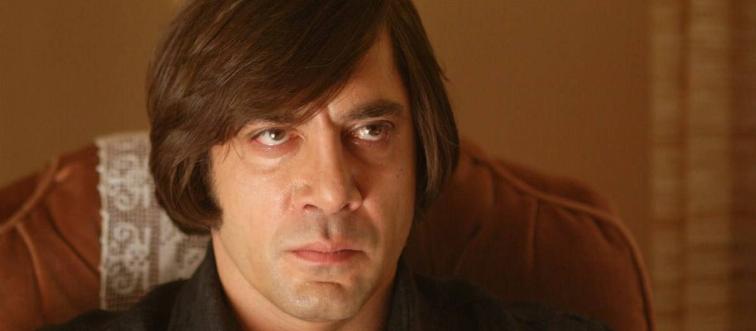 Javier Bardem sitting with angry face as Anton Chigurgh in No Country For Old Men