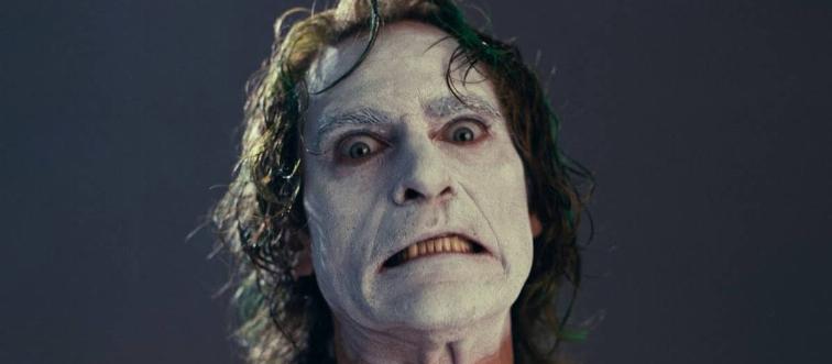 Joaquin Phoenix making a disturbed face with white makeup as Arthur Fleck in Joker