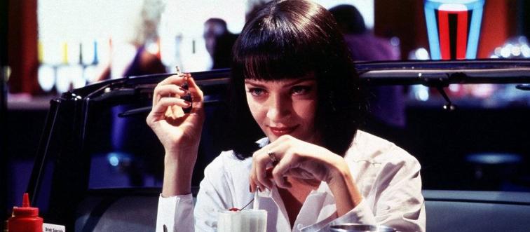 Uma Thurman sitting at 50s diner booth with milkshake as Mia Wallace in Pulp Fiction