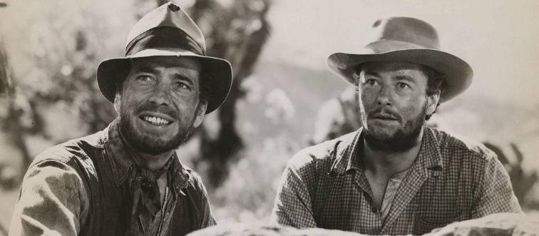 Humphrey Bogart and Tim Holt smiling in The Treasure of the Sierra Madre