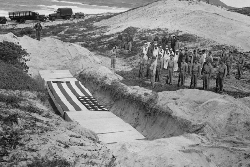 Military personnel pay their respects beside the mass grave of 15 officers and others killed in the attack at Pearl Harbor on December 7, 1941.