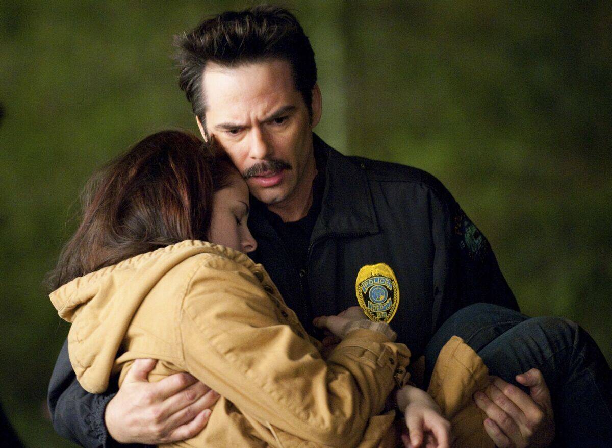 Billy Burke as Charlie Swann carrying Kristen Stewart as Bella Swann in his arms in Twilight New Moon