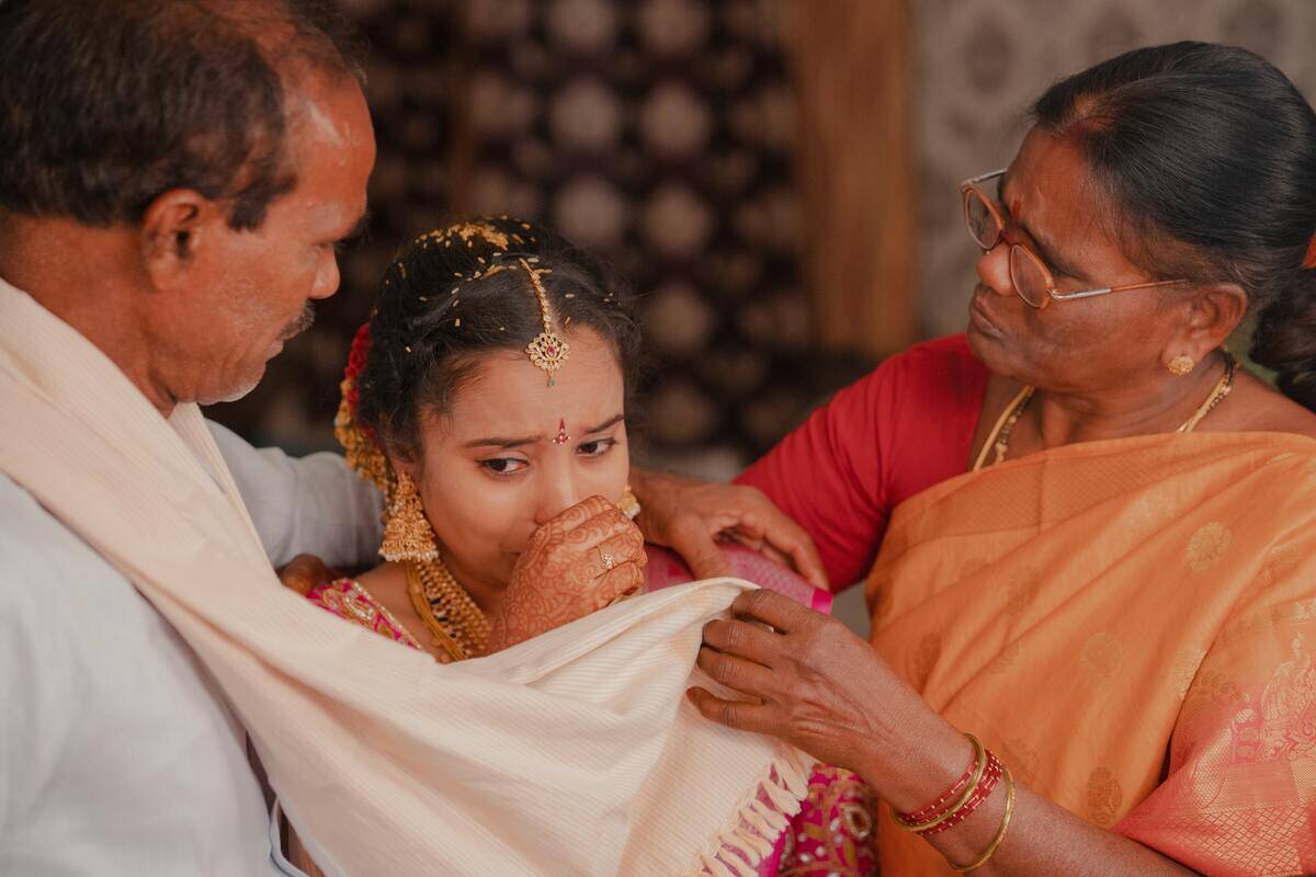 Bride crying while her parents comfort her