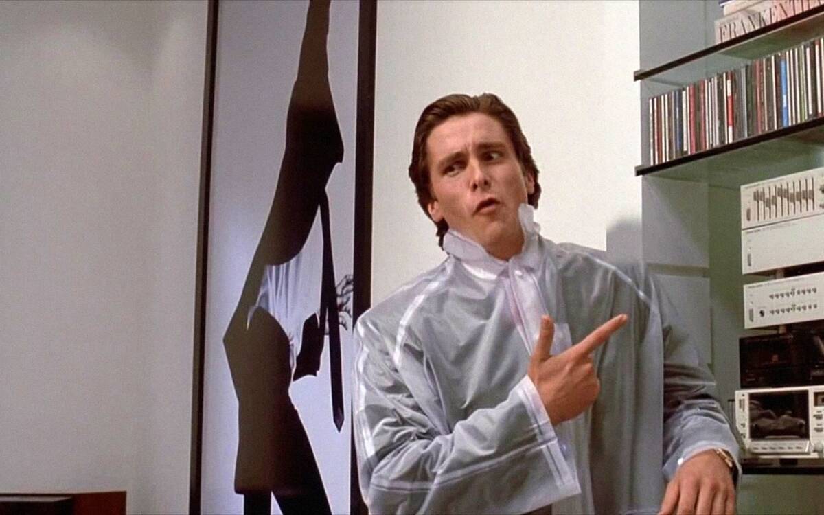 Christian Bale pointing to stereo with odd facial expression in American Psycho
