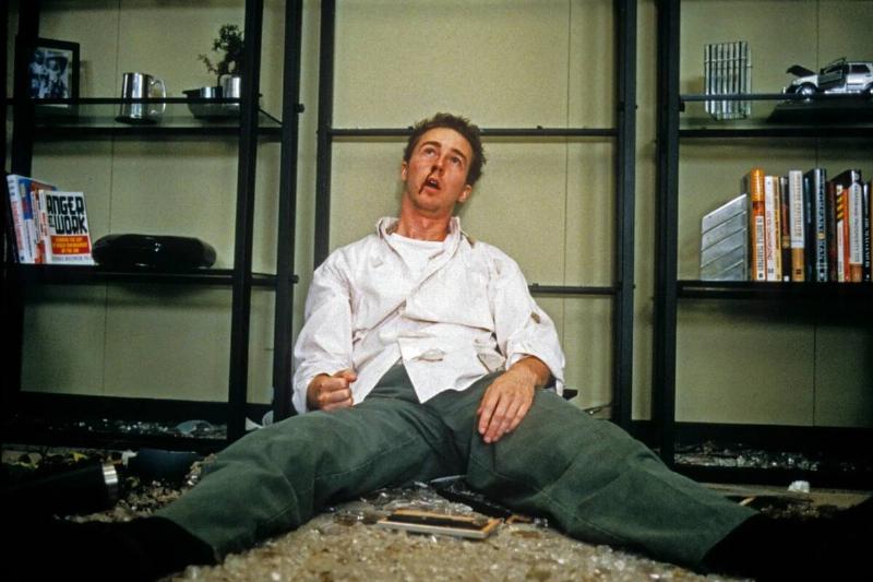 Edward Norton as [redacted] sitting against broken shelf in Fight Club