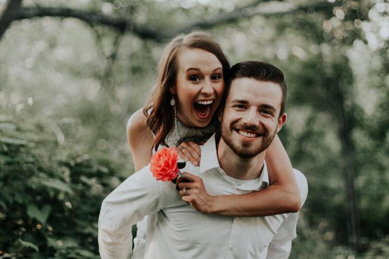 Man giving woman holding flower piggyback ride