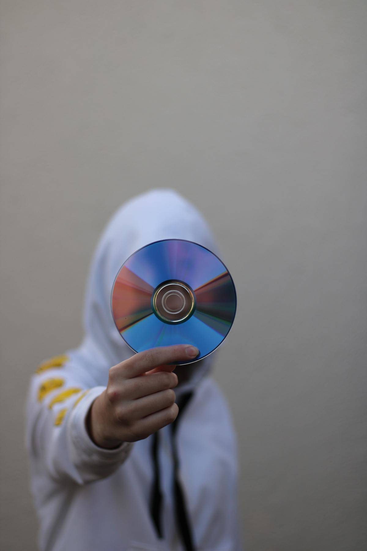 a person in a white hoodie holding a CD