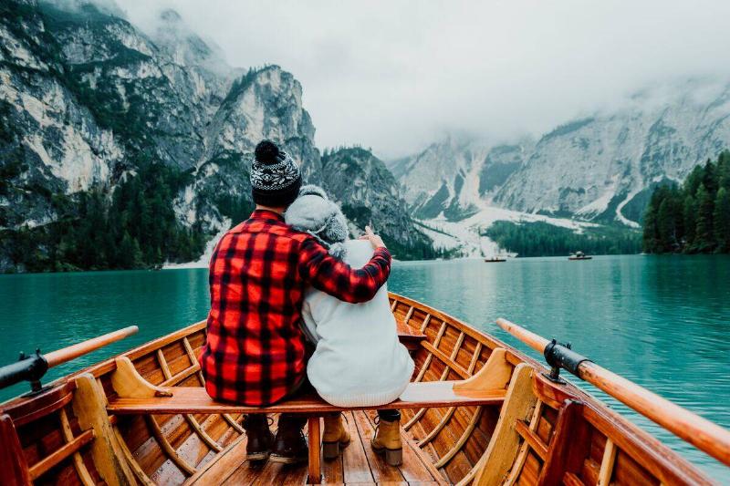 man and woman embracing on rowboat among glaciers