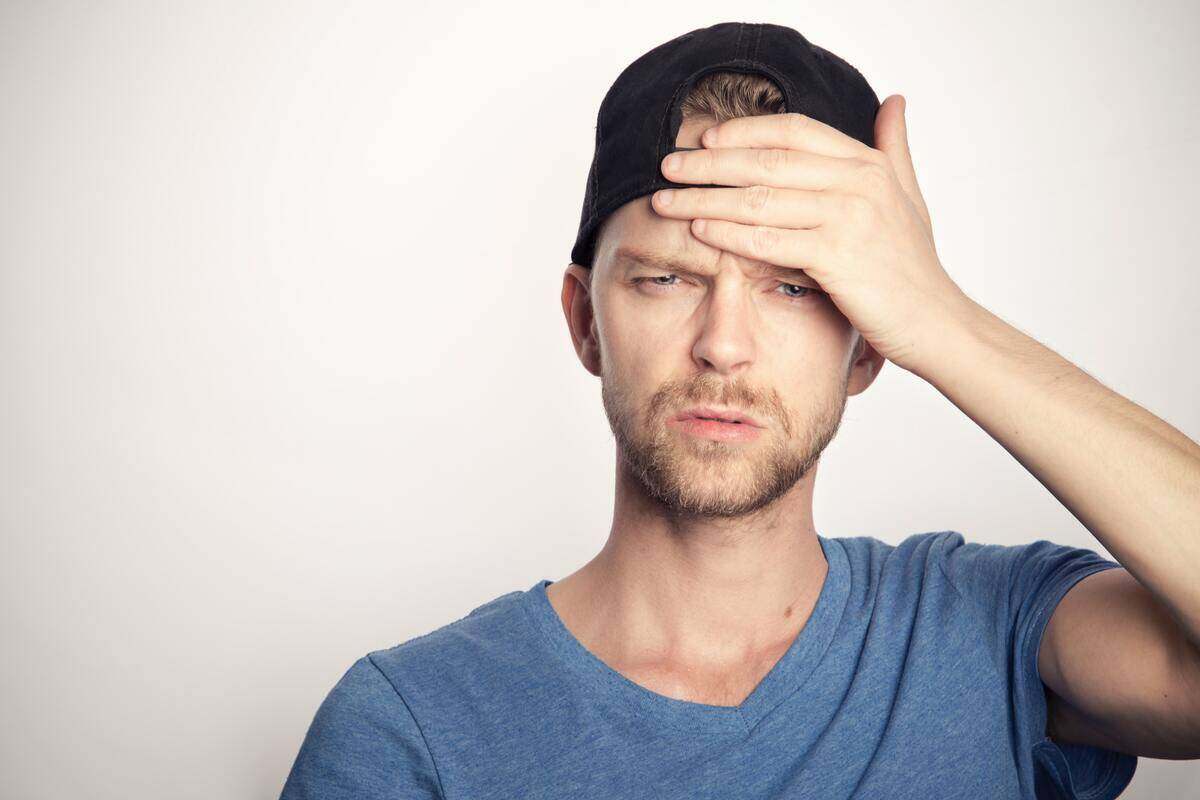 man in backwards baseball cap putting hand on his head in confusion.