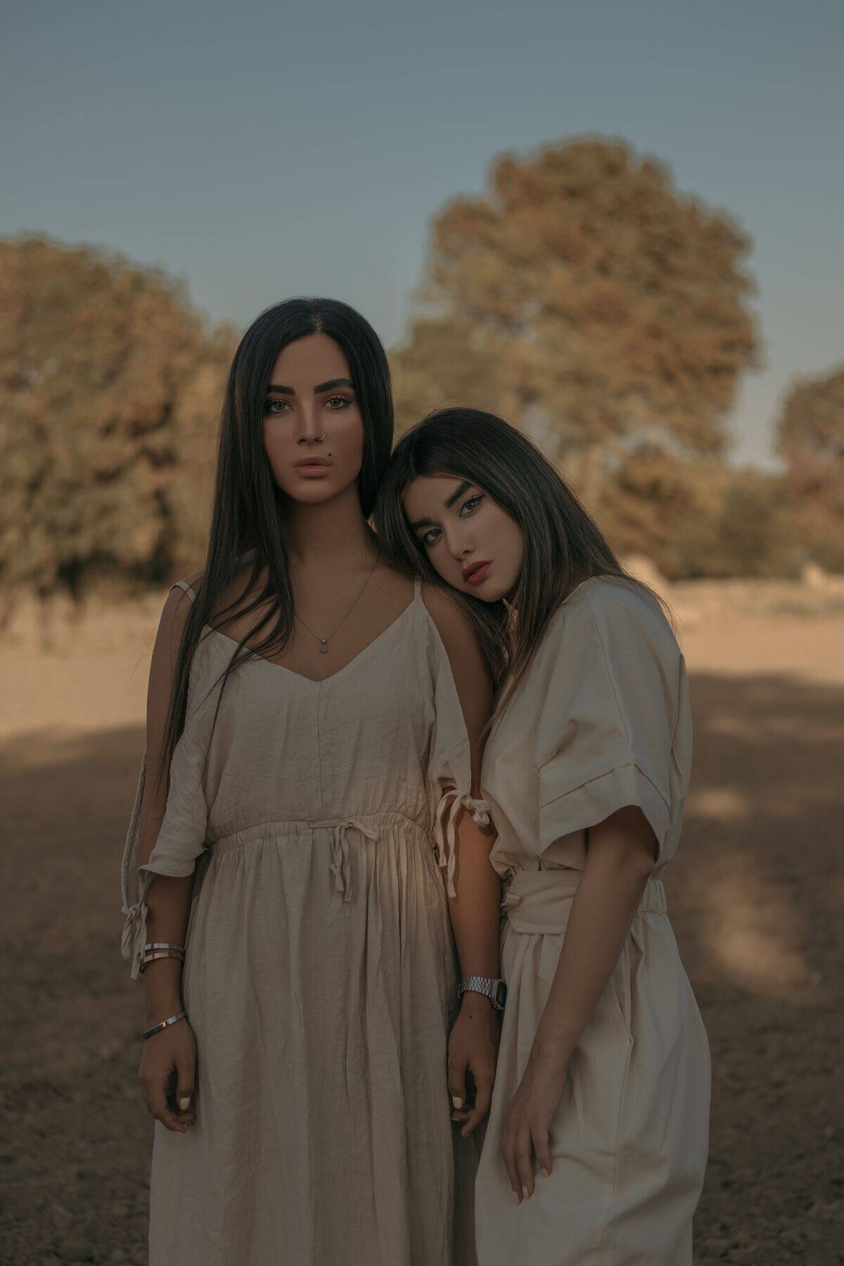 sisters standing together with beige dresses and serious faces