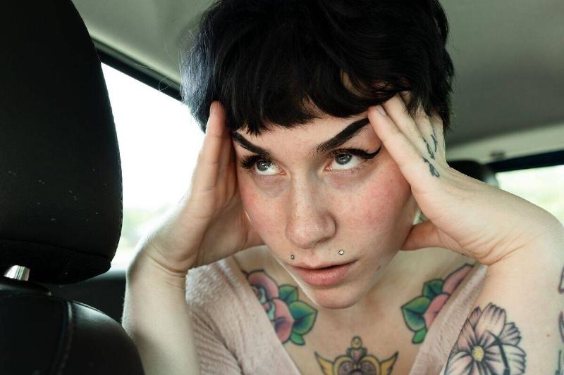 stressed woman touching her head in car's back seat