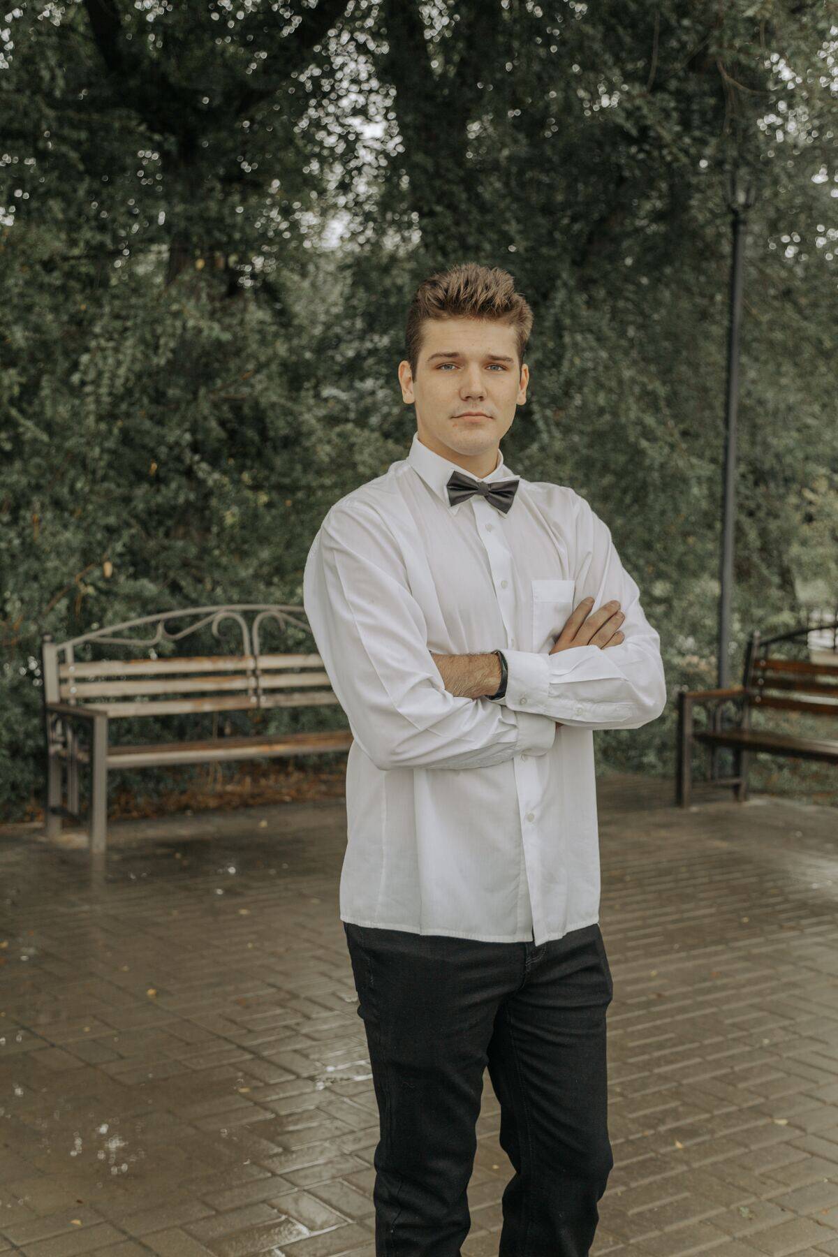 waiter standing with arms crossed in front of bench