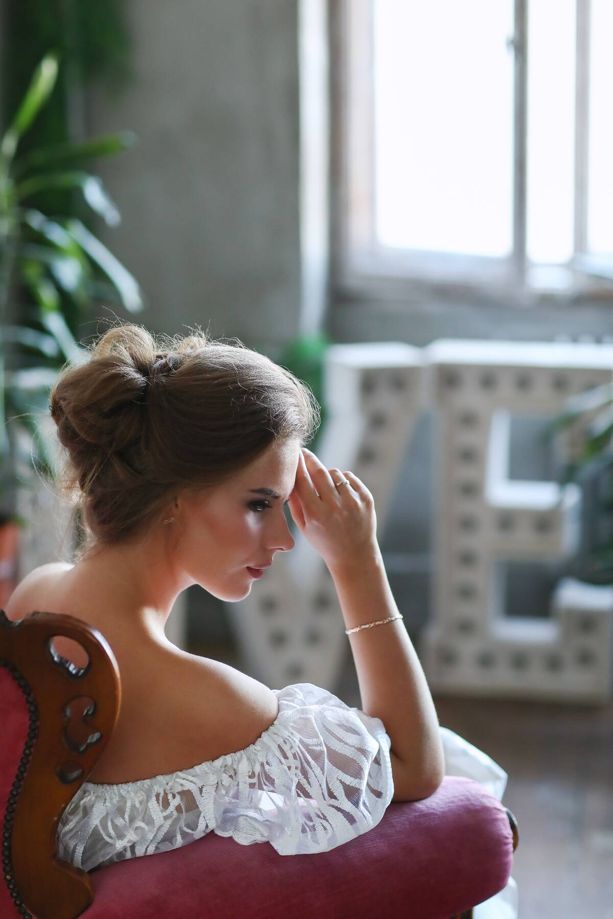 woman in bridal gown sitting in chair and touching her forehead