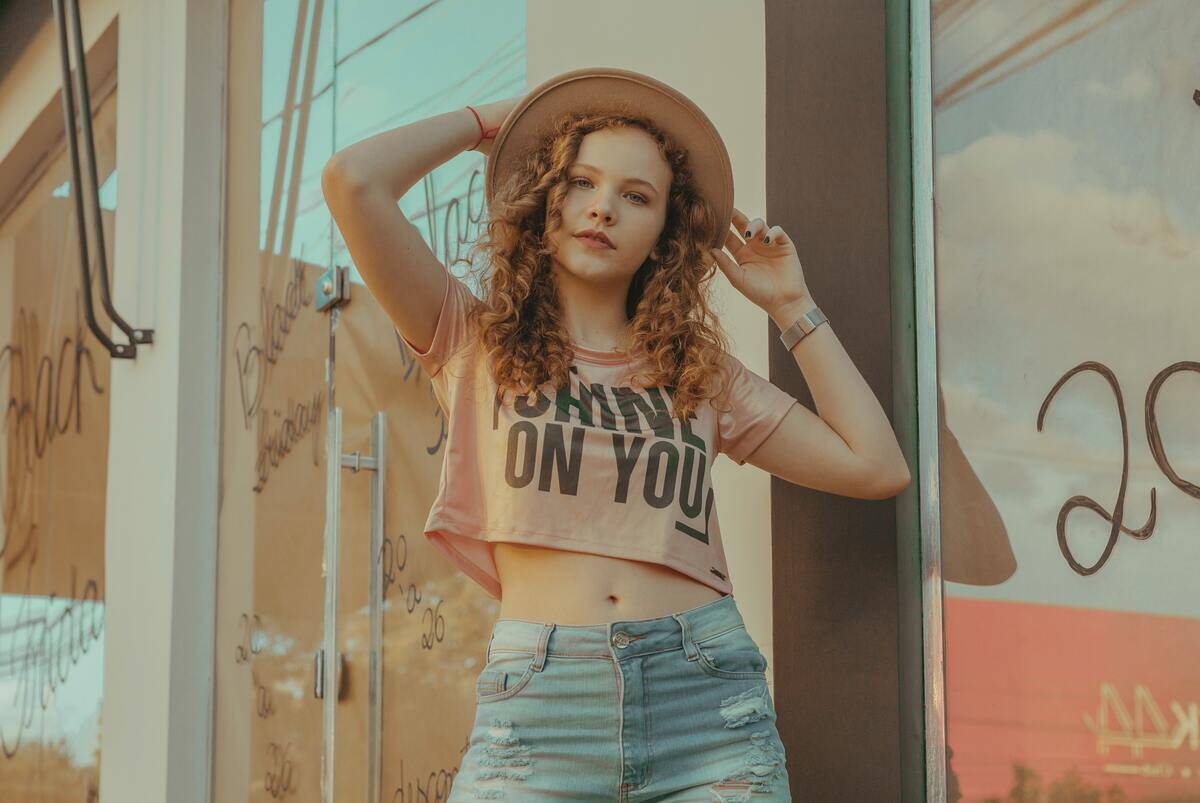 woman posing with hat and 'shine on you' shirt in front of storefront