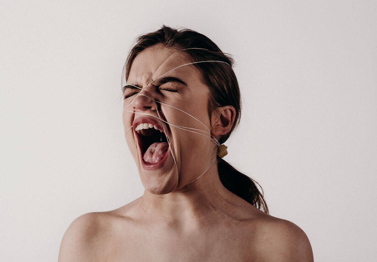 woman with face bound by string screaming