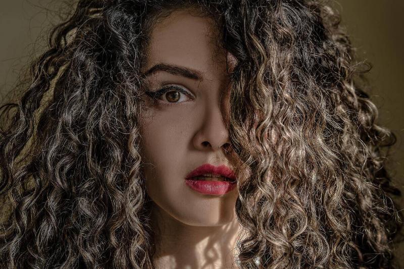 woman with long curly hair looking shocked