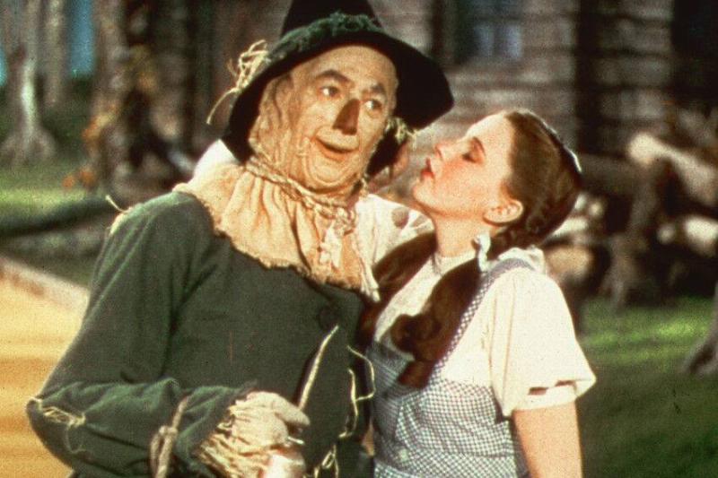 Judy Garland as Dorothy Gale standing next to Ray Bolger as the Scarecrow with her eyes closed in The Wizard of Oz