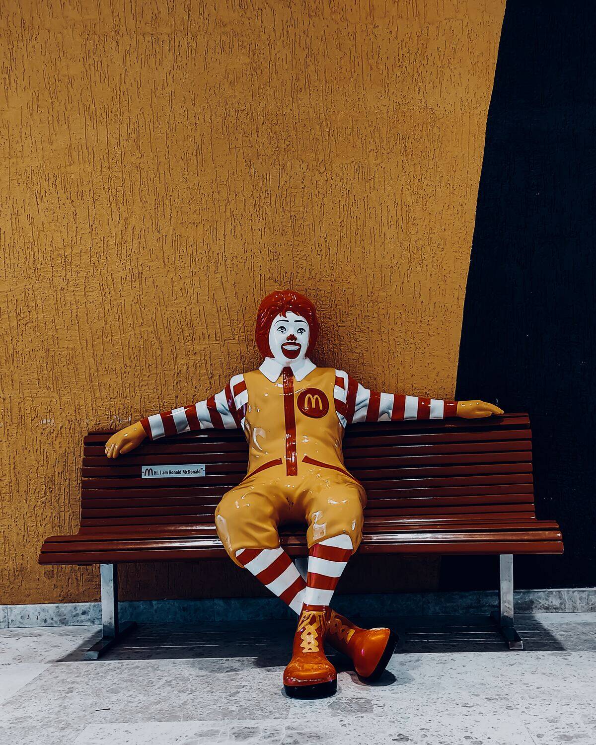 Ceramic Ronald McDonald statue lounging on bench