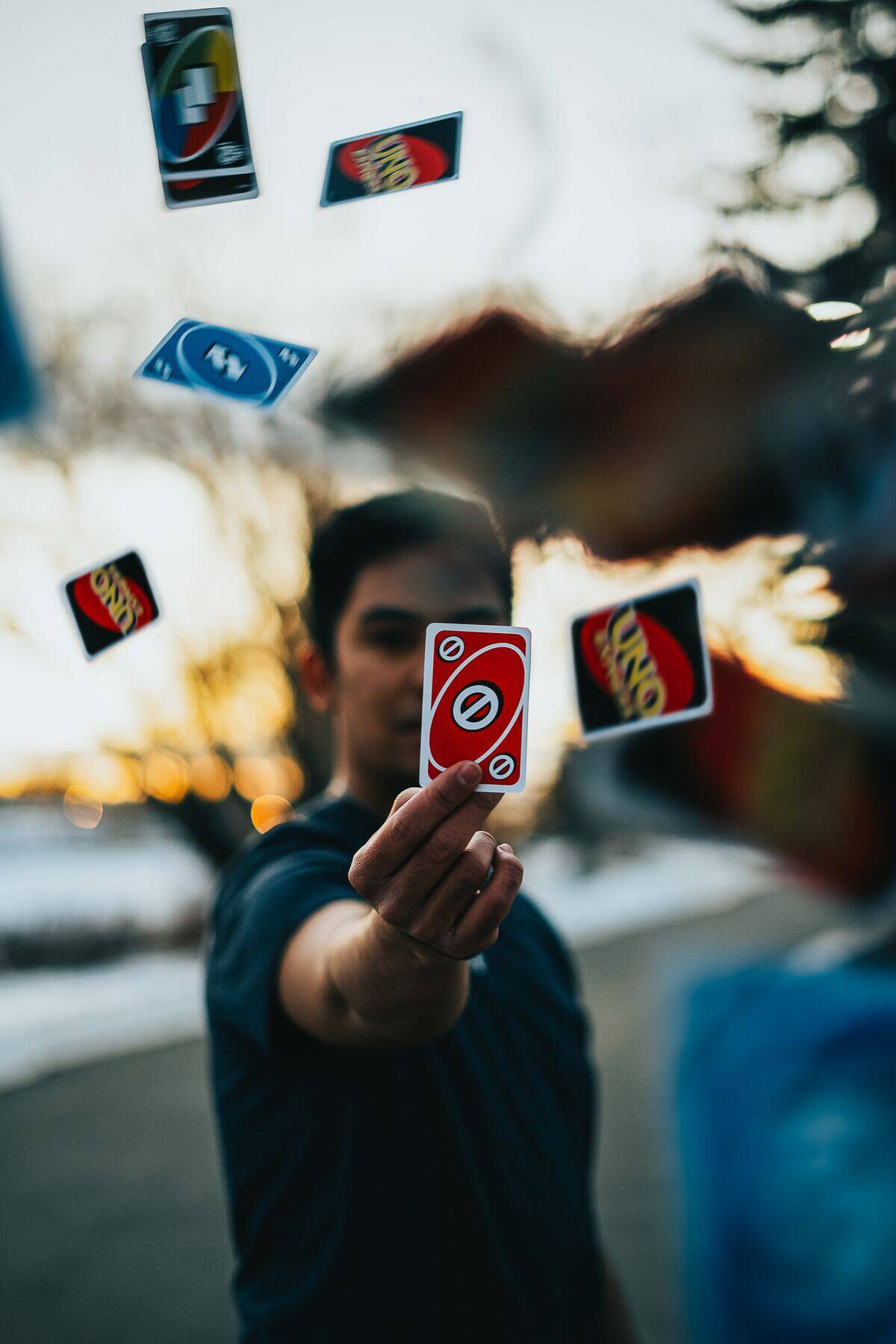man holding out uno card while others fly around him