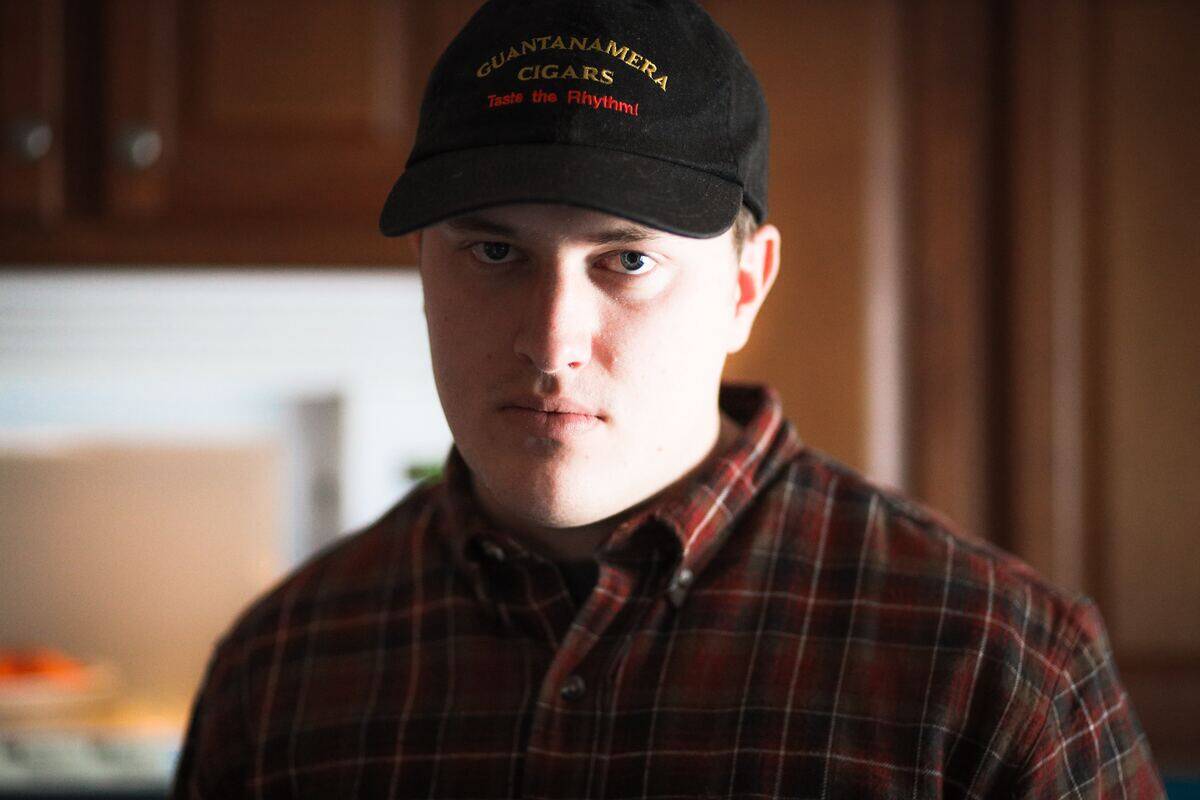 man in baseball cap angrily standing in kitchen