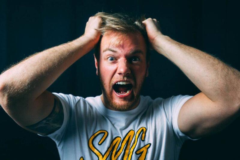 man with hands on his head while yelling in rage