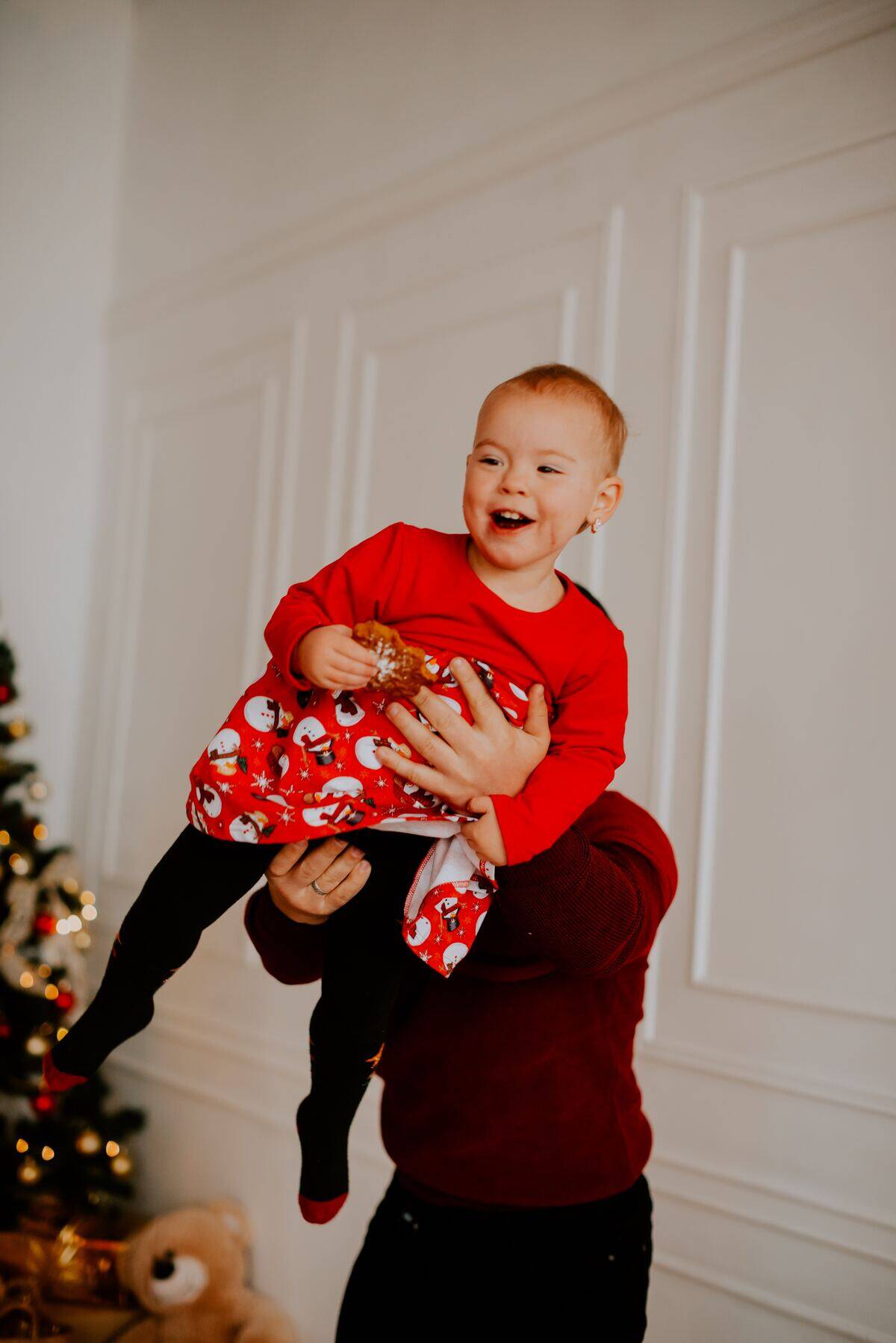 parent lifting little girl eating Christmas cookie