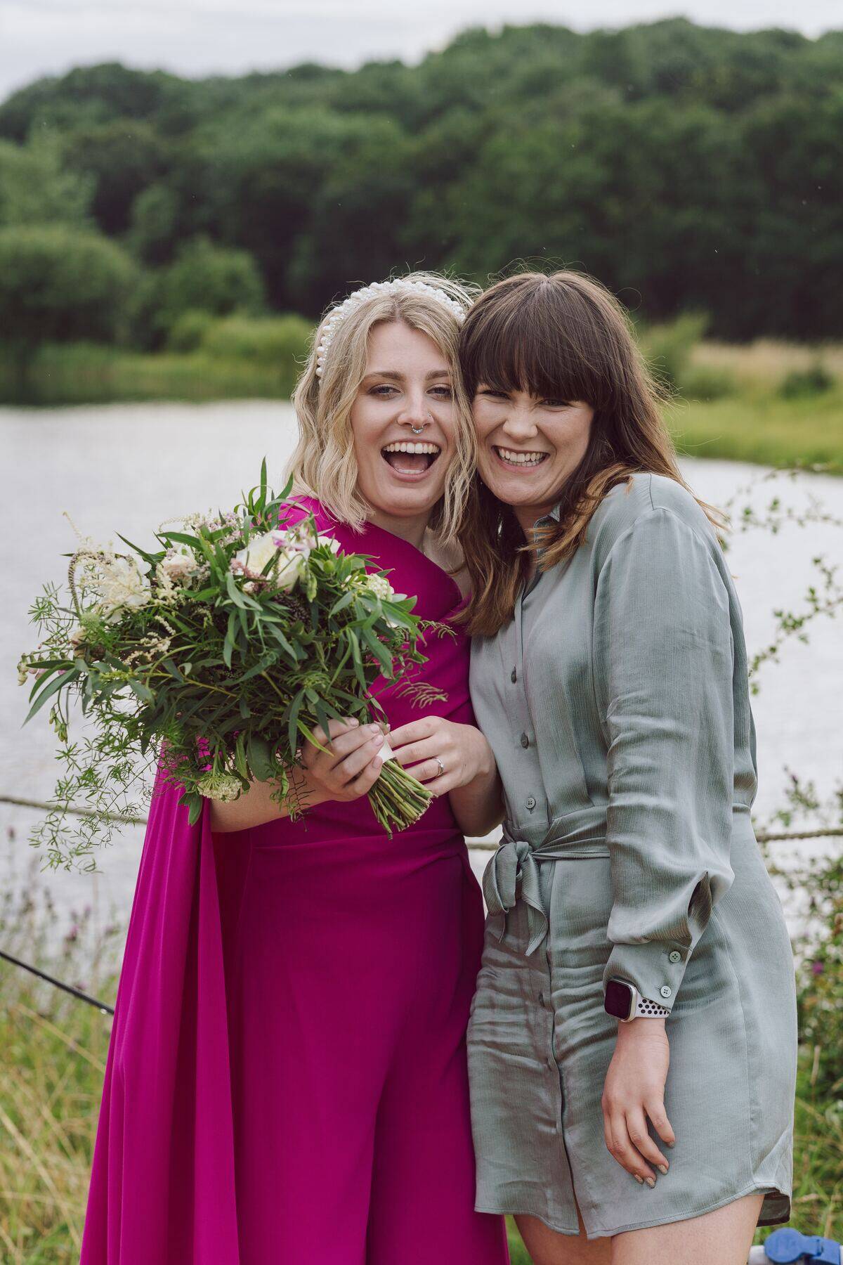 woman holding flowers while standing happily next to other woman