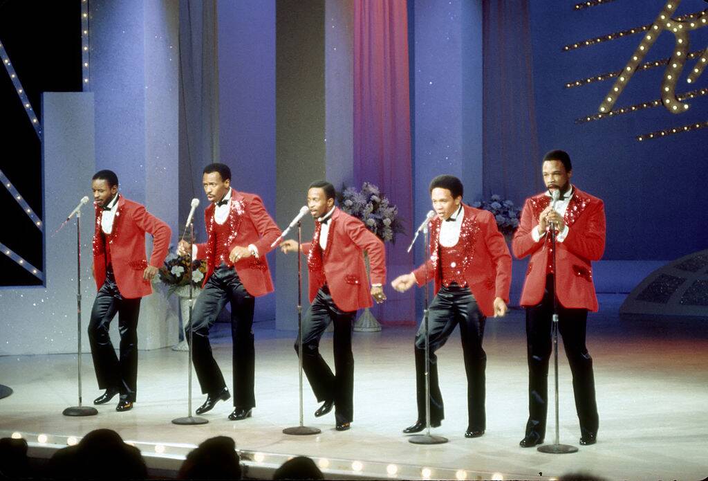 band performing on stage wearing matching suits
