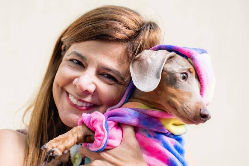 dachshund woman holding a dachshund dog in a colorful outfit