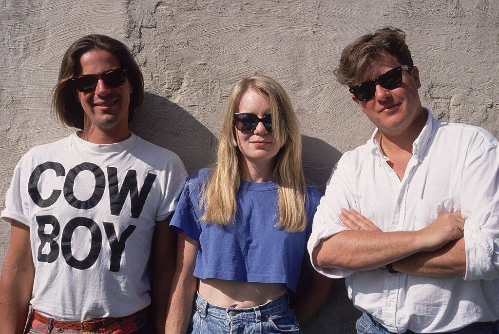 two men and a woman standing by a wall