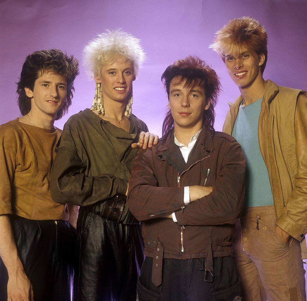 band members in front of purple background