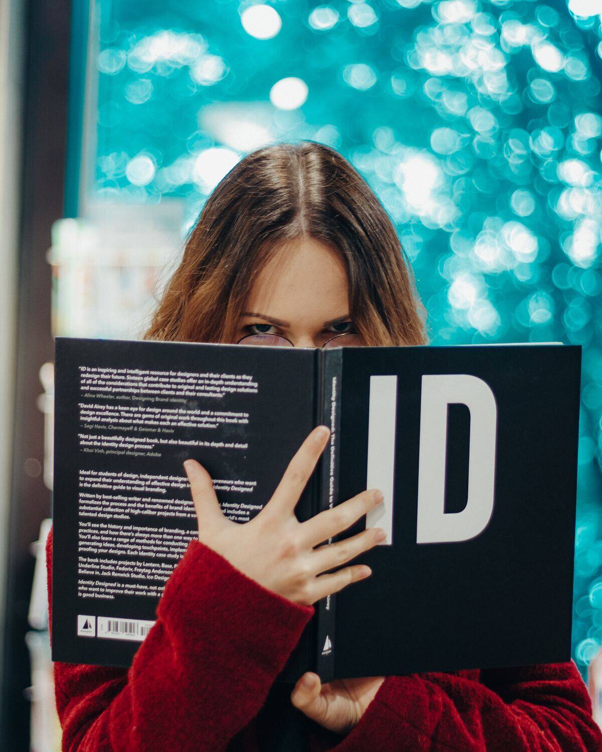 woman in glasses angrily peeking over book