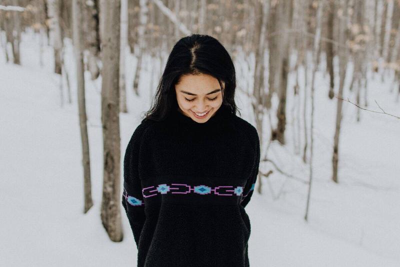 woman looking down bashfully amid winter forest