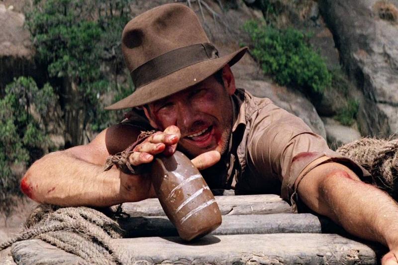 Harrison Ford smiling while holding bottle in Indiana Jones And the Temple Of Doom