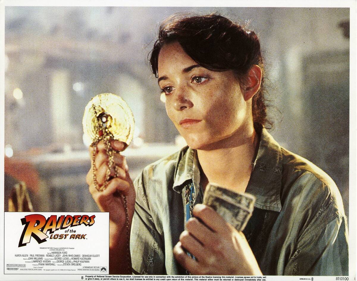 Karen Allen holding money and jewelry as Marion Ravenwood in Raiders Of The Lost Ark