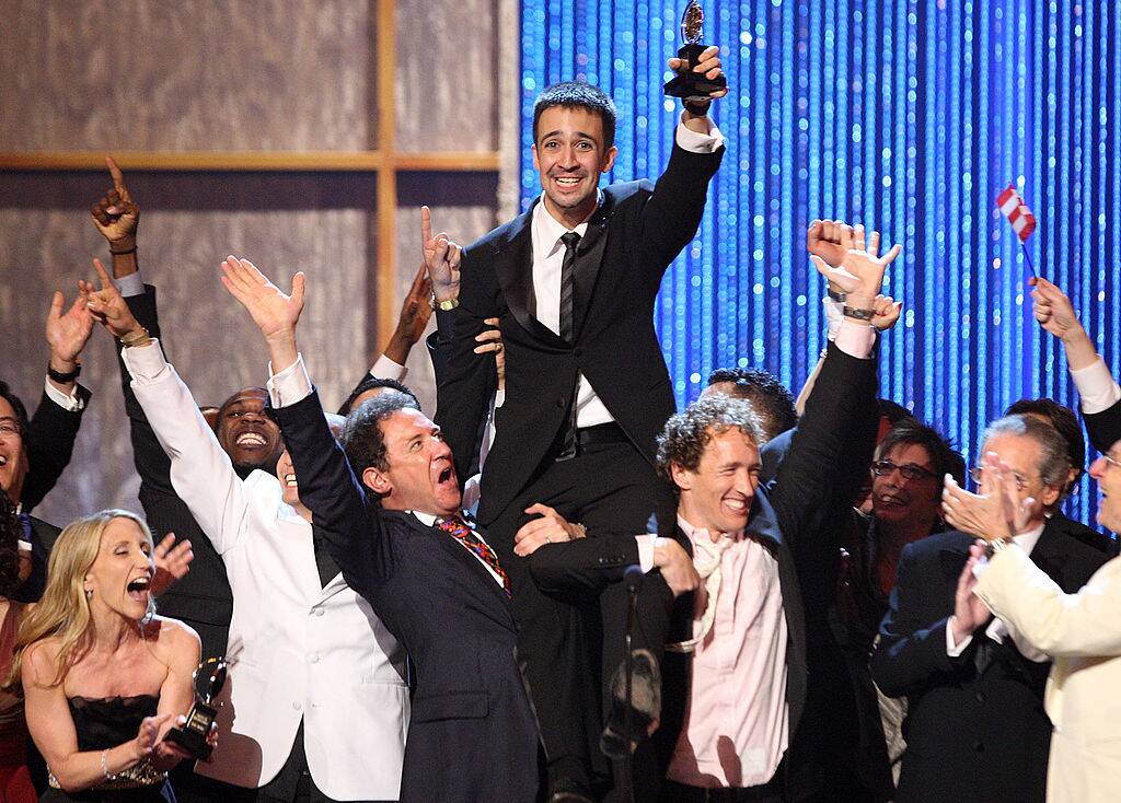 man holding up a tony award