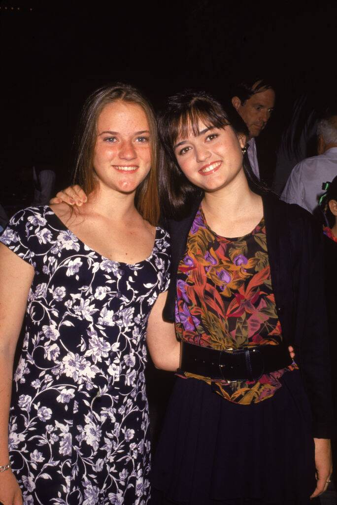 sisters Danica McKellar (right) and Crystal McKellar stand with their arms around each other, early 1990s