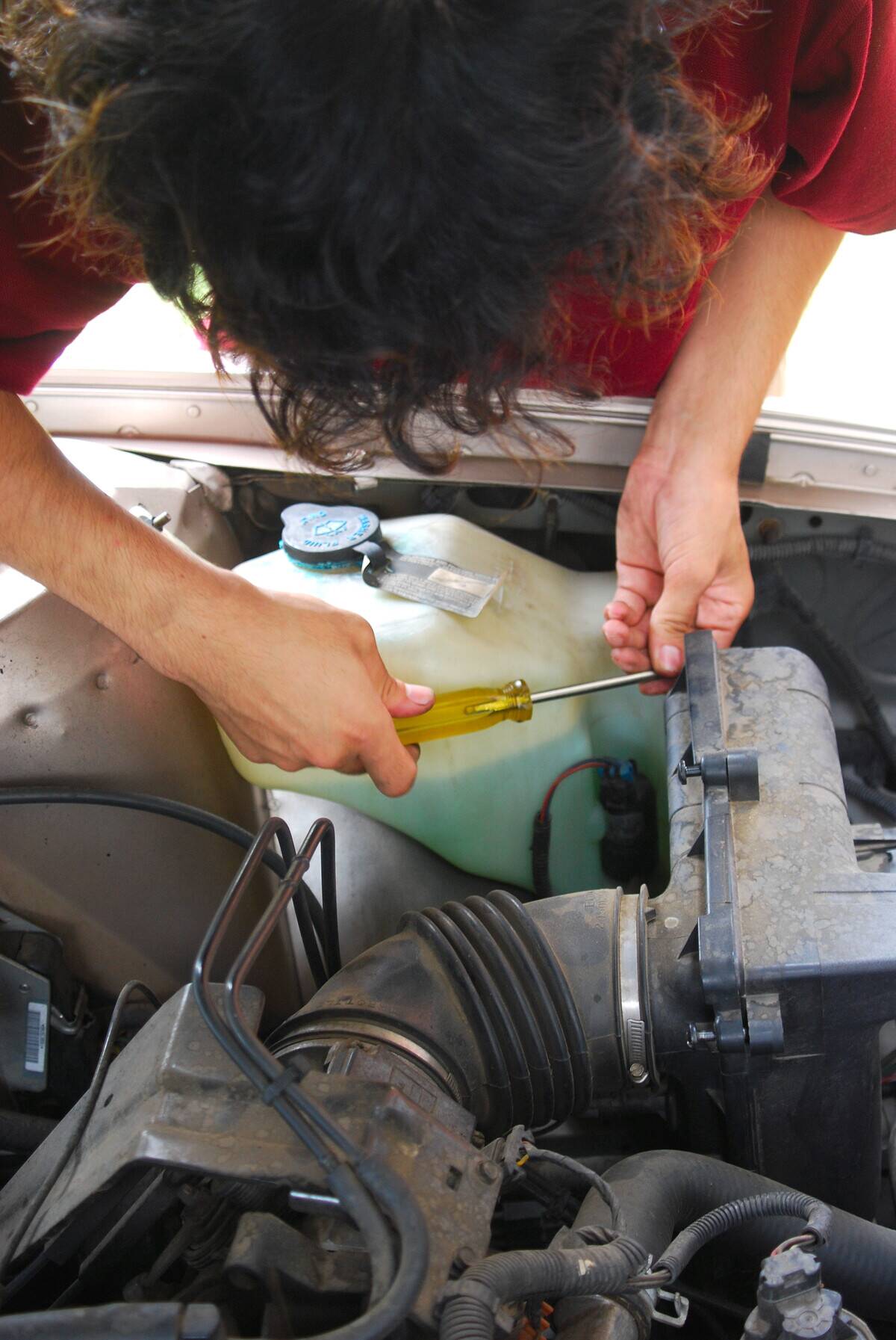 A mechanic working on a Buick automobile, using a screwdriver.