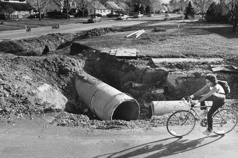 NOV 6 1981, NOV 7 1981; Randy Martinex, 13, of 2590 W. College Ave., pedals past excavation at West