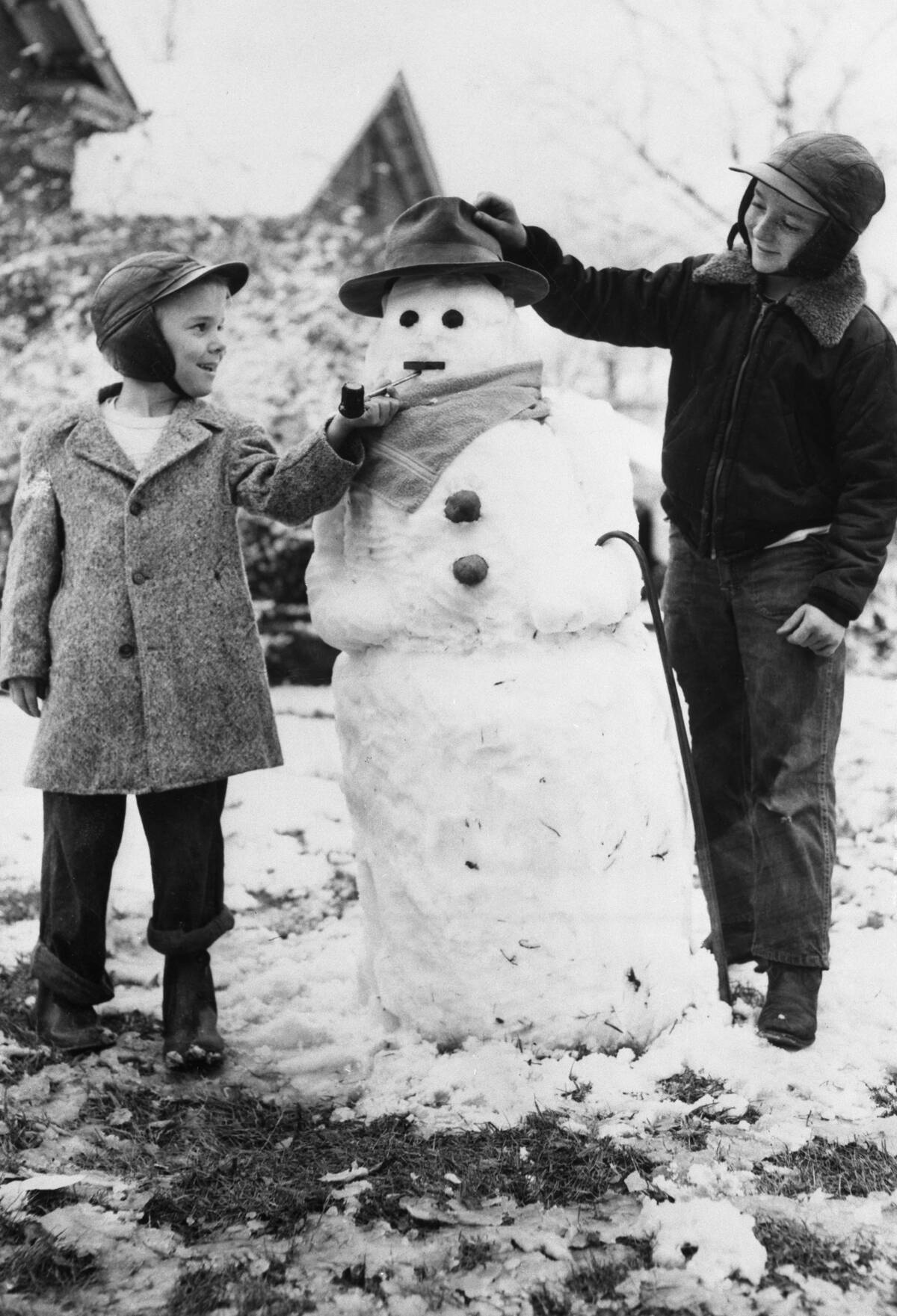Two boys (8-9) posing with snowman