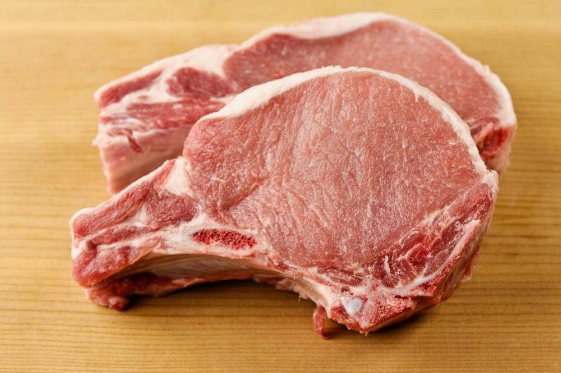 Two raw t-bone steaks on a wooden cutting board