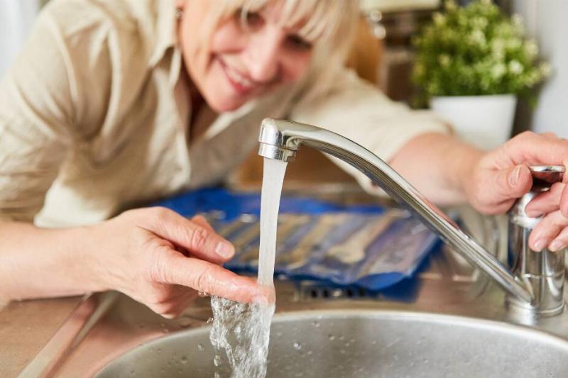 345 Woman running water from tap over finger.