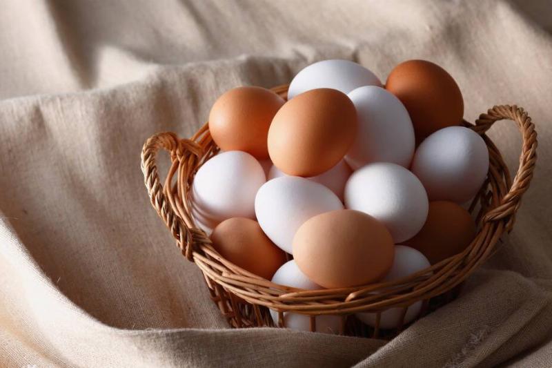 Brown and white eggs in a wicker basket that's within a sheet