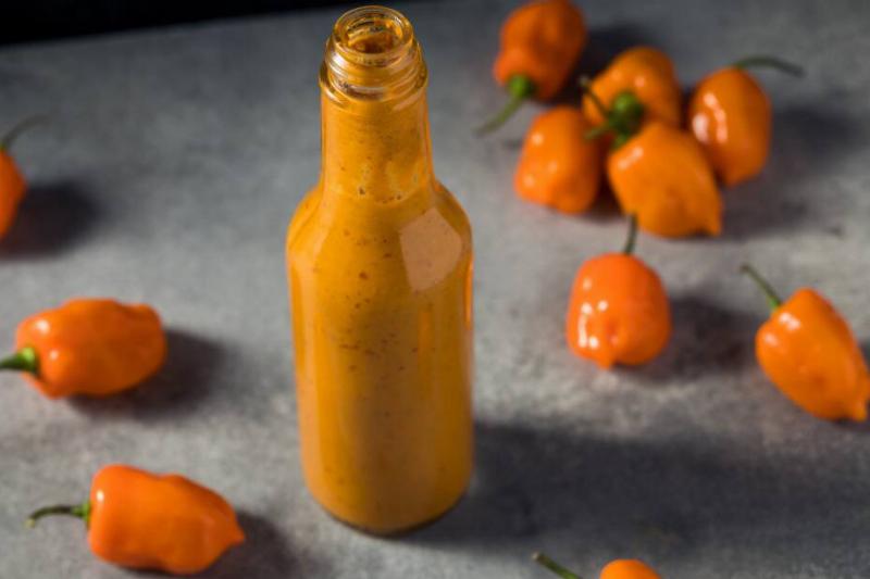 Peppers surrounding a jar of hot sauce