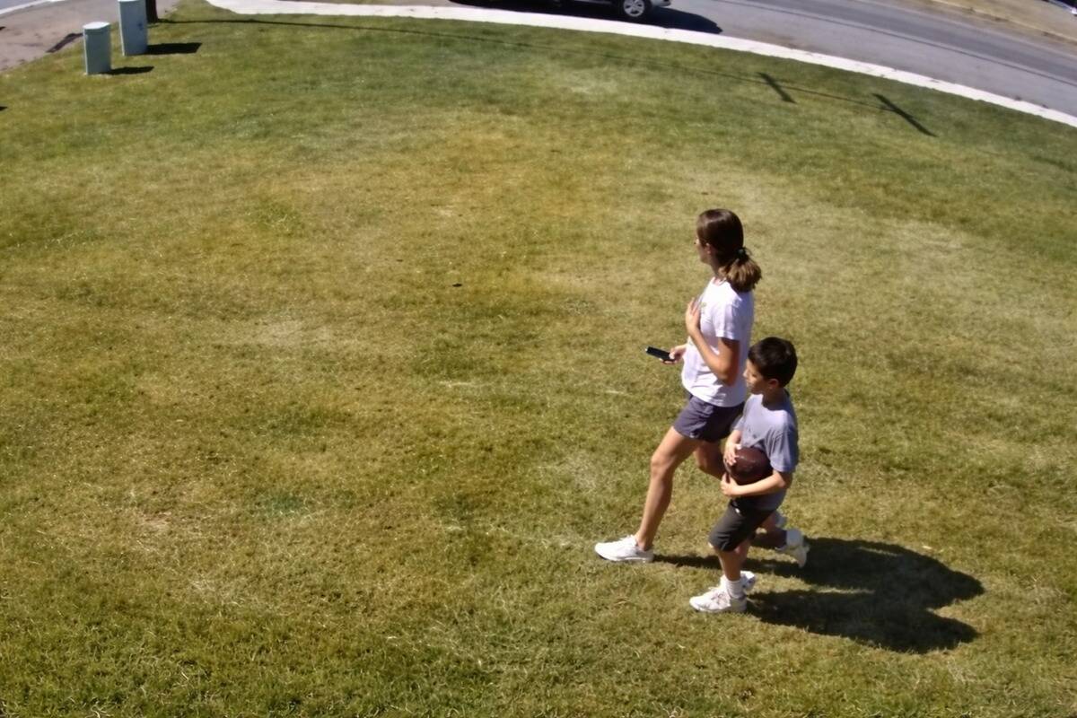 Woman and male child walking across a front yard