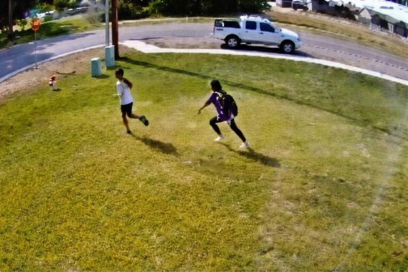 Two young girls running across a front yard