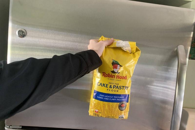 A bag of flour in front of a fridge.