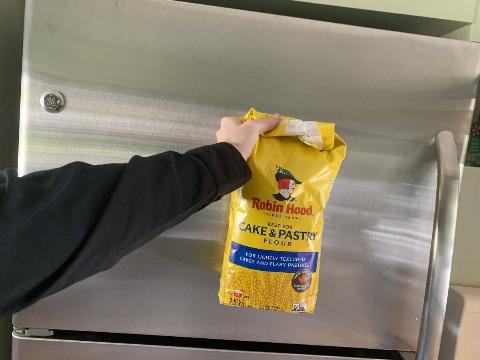 A bag of flour in front of a fridge.