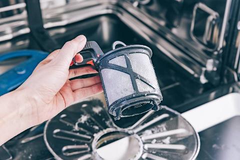 A man cleaning a dishwasher filter.